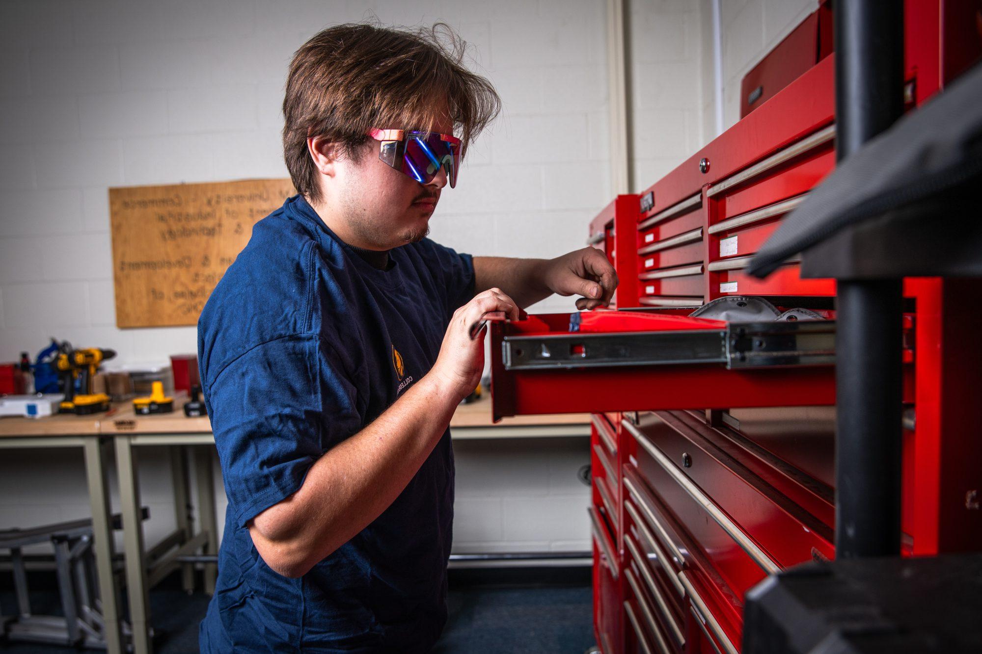 A male looking through a tool case.